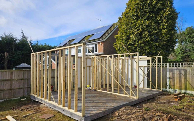 empty room with plastered walls and wooden flooring featuring a door and large windows creating a spacious renovation project for two potential uses