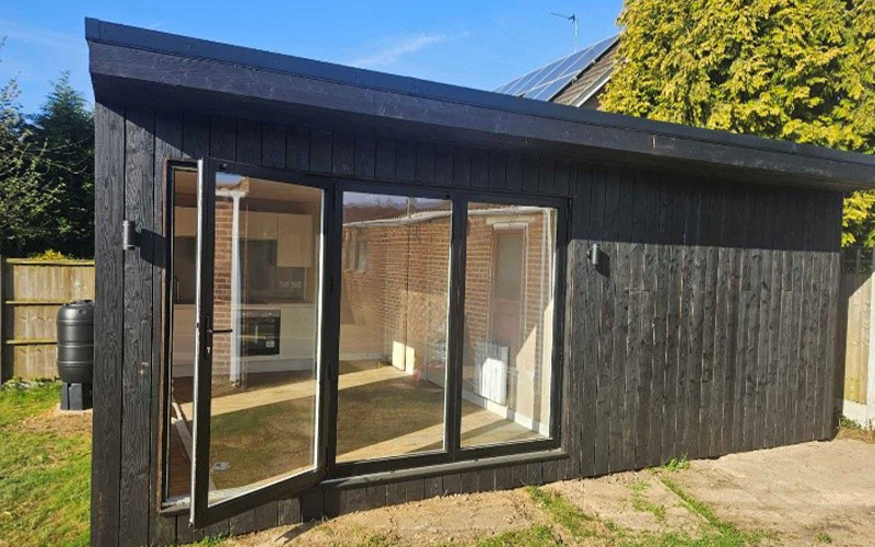 construction of a new shed with wooden frame and white walls in backyard with exterior ladder and unfinished interior suitable for outdoor projects and storage