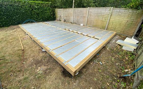 construction of a new building with wooden framing and a basic foundation in a residential area featuring a house with solar panels in the background twelve essential steps for home renovation