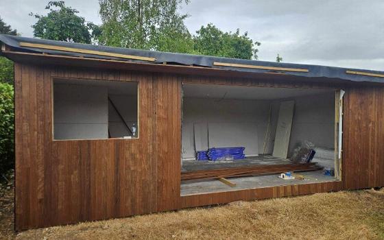 modern black cabin exterior with large windows showcasing garden and interior space featuring energy efficiency design and 8 sustainable features