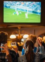 two beer mugs clinking together in celebration with frothy tops in a warm bar setting